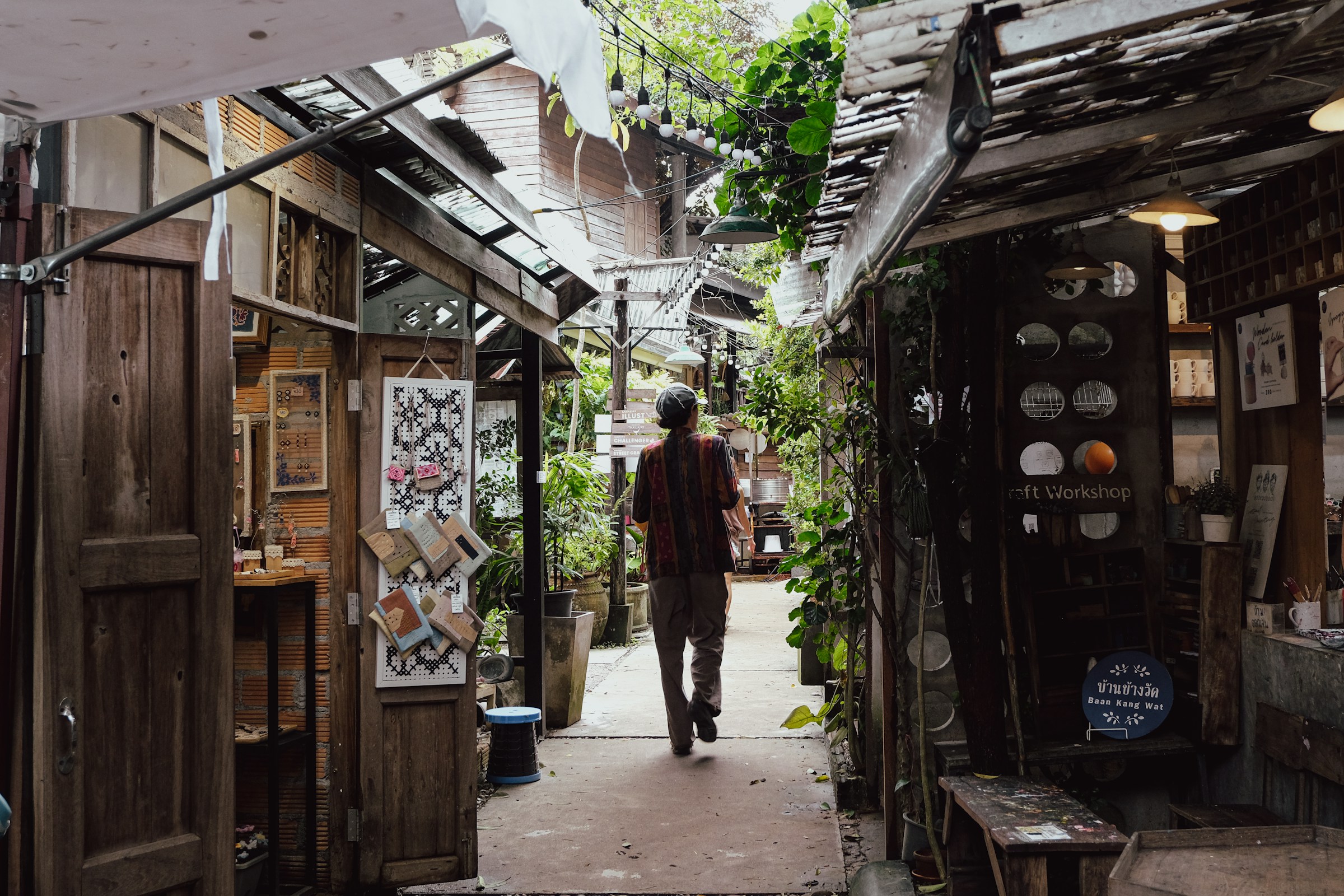 Person walking down a narrow alleyway lined with shops